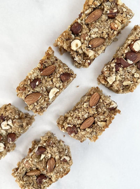 Granola bars made with oats, sunflower seeds, coconut flakes, nuts, and honey on parchment paper