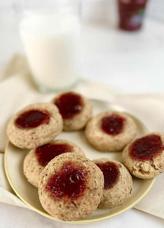 almond cookies with jam filling made using almond pulp, served on a white plate